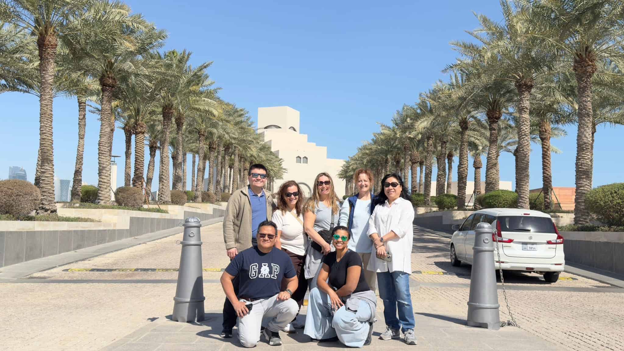 Group of tourists visiting Dubai's famous landmark with palm trees and modern architecture.